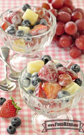 Footed dessert glasses filled with a fruit mix coated in yogurt.
