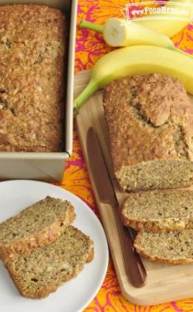 A loaf of Banana Oatmeal Bread is sliced to show a golden brown top and moist inside texture.