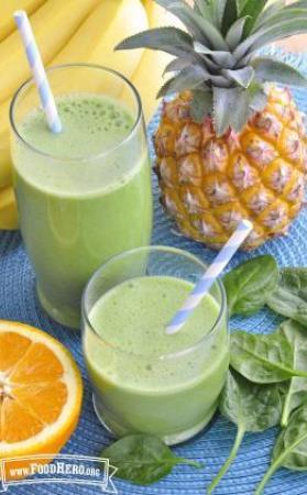 Glasses of green fruit smoothies with straws.