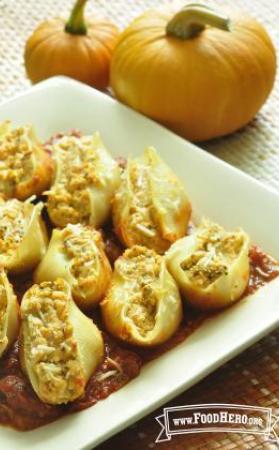 Plate of pasta shells filled with pumpkin and cheese filling over red pasta sauce.