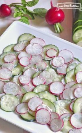 Platter of thinly sliced cucumbers and radishes with a seasoned yogurt sauce.