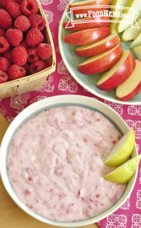 Bowl of yogurt raspberry dip served with sliced apple and pear.