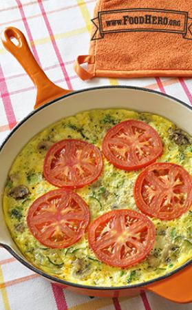 Pan of vegetable and egg mix topped with tomato slices.