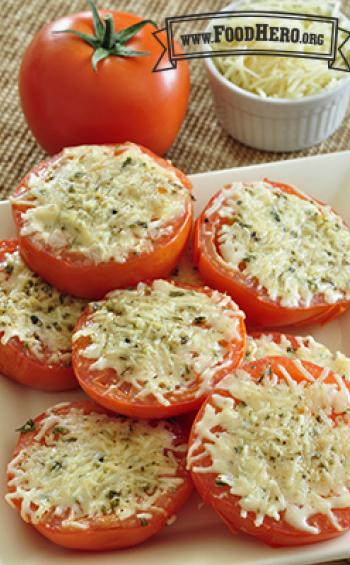 Sliced tomatoes with herbs and broiled cheese are shown on a serving platter. 