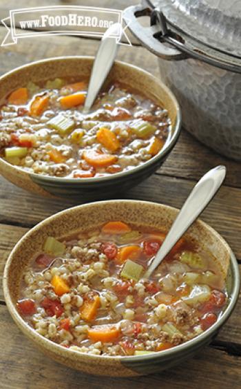 Two bowls are filled with a hearty soup made with vegetables, ground beef and barley.