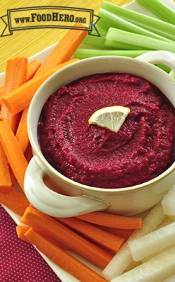 A bowl of beet dip is served with jicama, carrot and celery sticks.