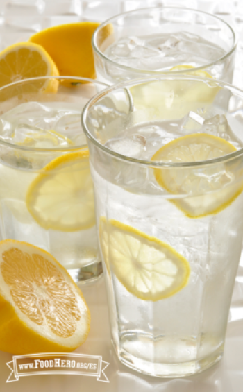 Vasos de agua helada con rodajas delgadas de limón amarillo.