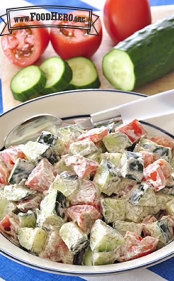 Bowl of chopped cucumber and tomatoes with a creamy dressing.