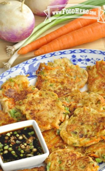Plate of crispy vegetable pancakes with dipping sauce.