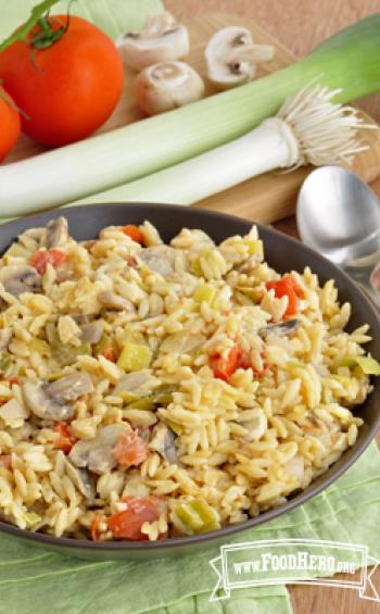 Medium bowl of a saucy orzo dish with vegetables.