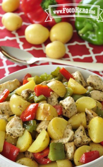 Bowl filled to the brim with baked bite-size potatoes, chicken and bell peppers.