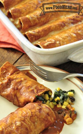 Casserole dish with tortillas filled with a bean, corn and spinach mix with red sauce.