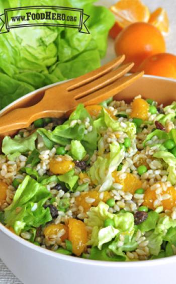 Bowl of mandarin orange and barley salad with a wooden serving fork.