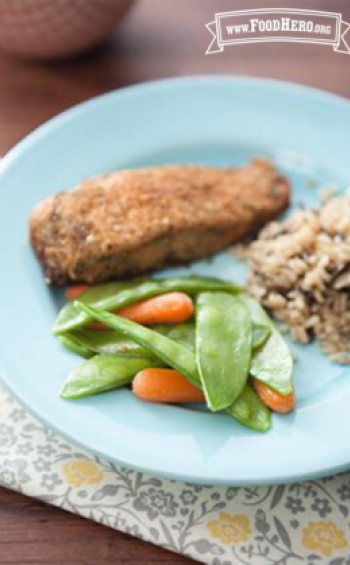 Baby carrots and snow peas on a plate with rice and fish.