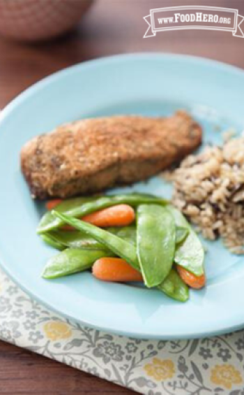 Baby carrots and snow peas on a plate with rice and fish. 