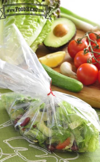 Plastic bag holding salad and dressing.