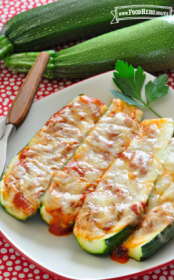 Plato con mitades de calabacita al horno rellenas con salsa roja y queso derretido.