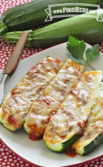 Plate of baked zucchini halves filled with red sauce and melted cheese.