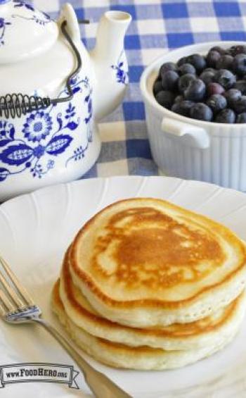 Stack of golden pancakes with a side of blueberries.