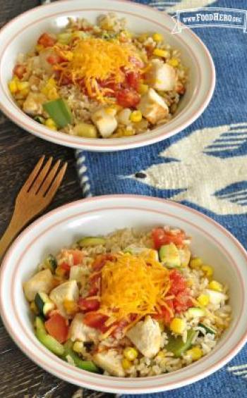 Bowls of rice, vegetables and chicken with shredded cheese.