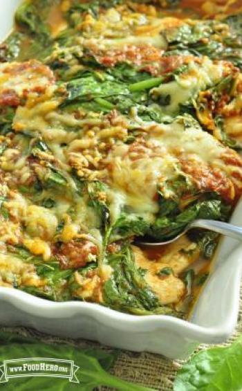 Baking dish with chicken, spinach, sauce and cheese.