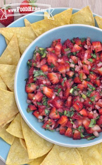 Bowl of bright green and red Strawberry Salsa served with tortilla chips.