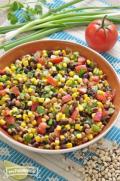 Corn, bean and vegetable mix with dressing in a large bowl.